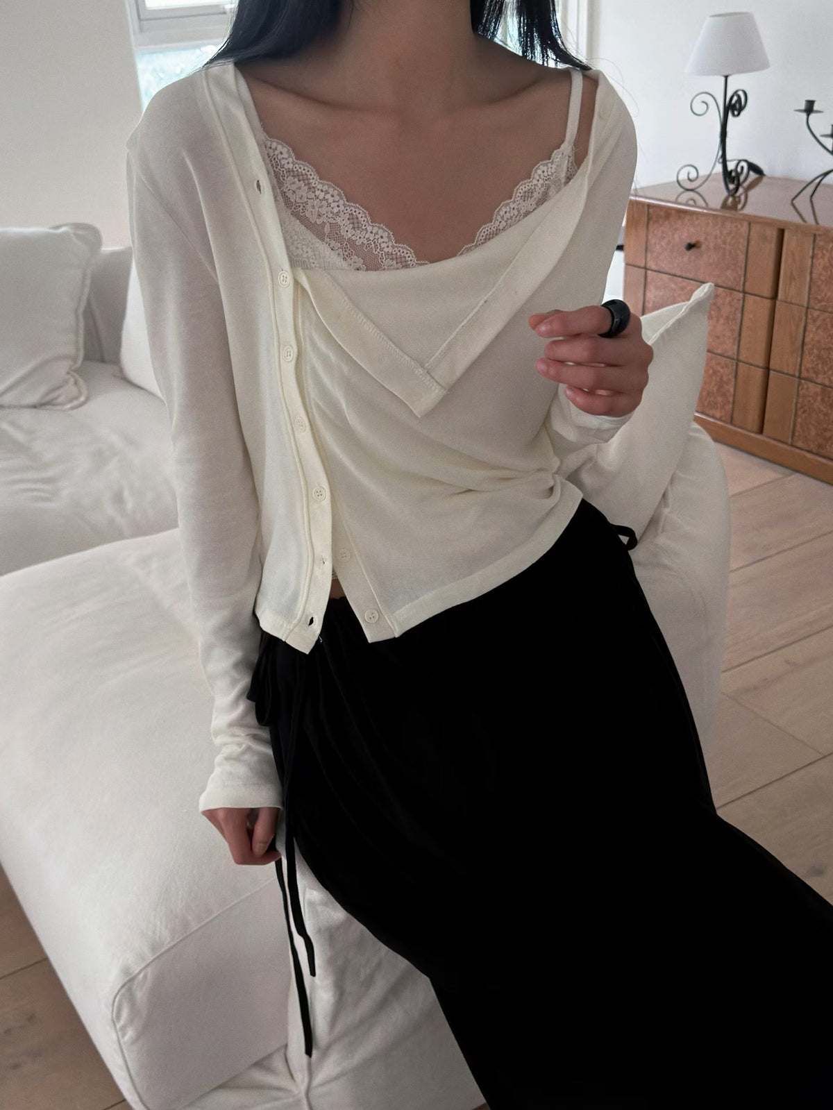 Close-up of an ivory cardigan showing the draped neckline and asymmetric button placket.