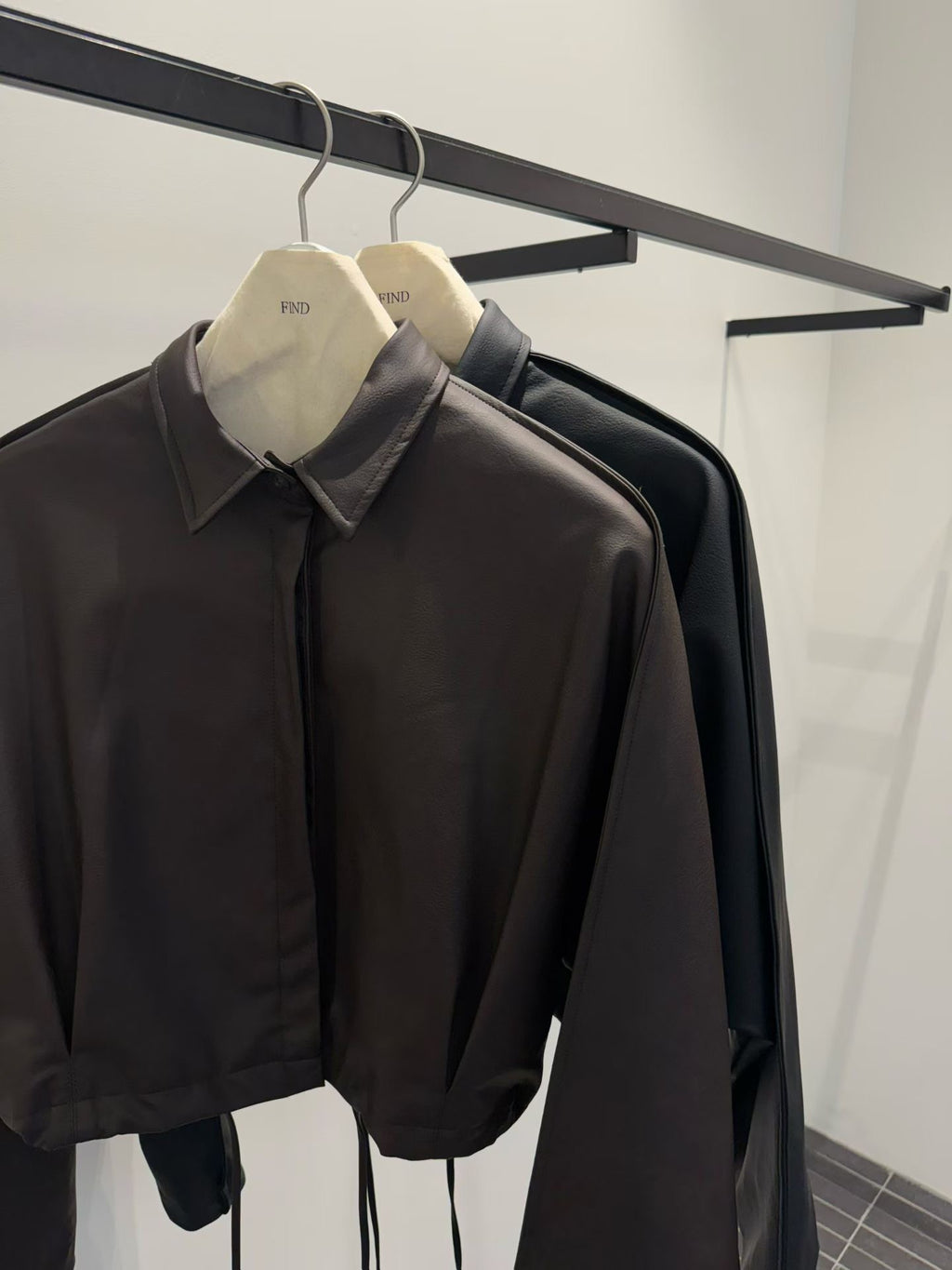 Brown and black faux leather jackets on hangers, close-up of pointed collars