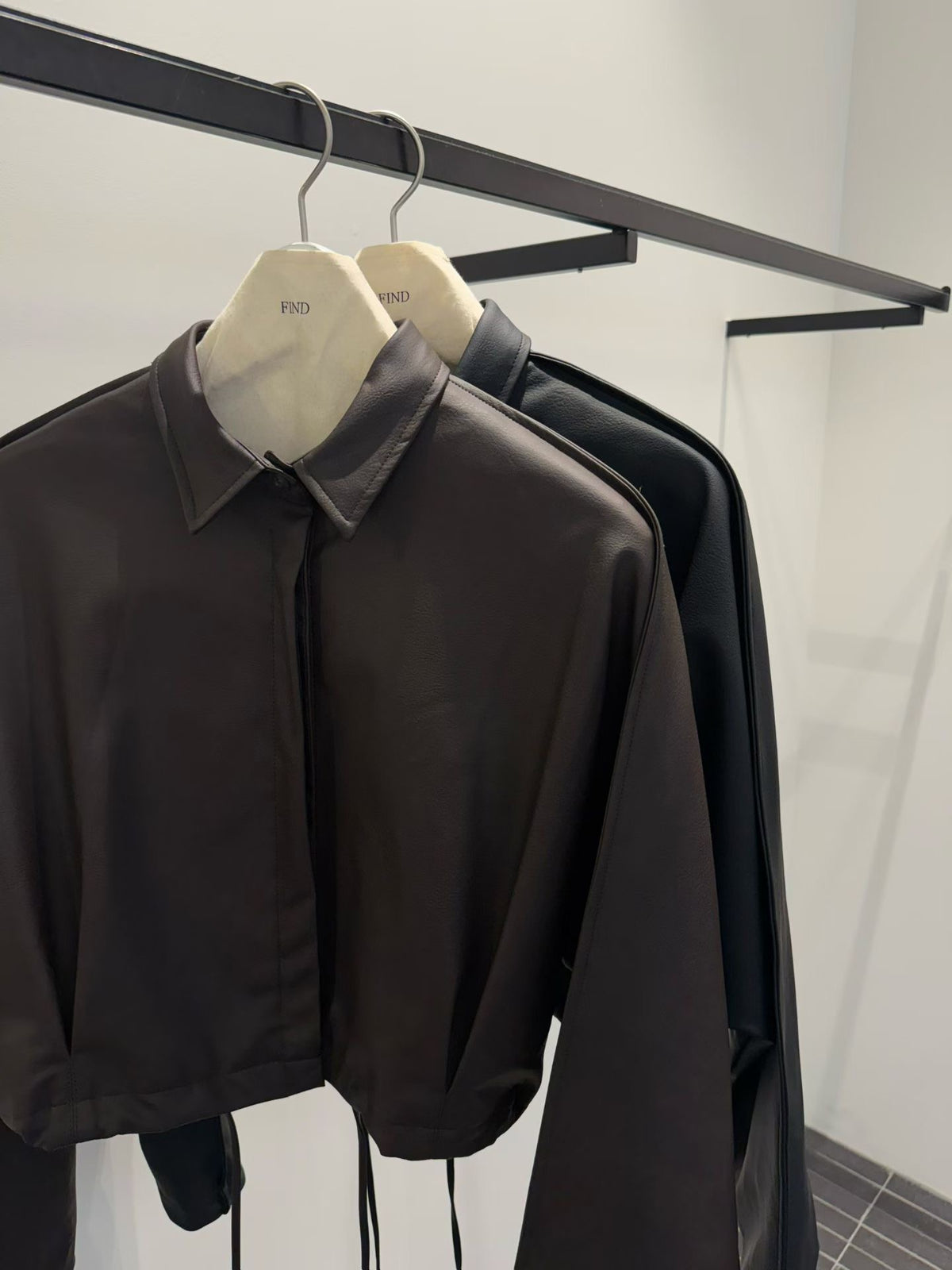 Brown and black faux leather jackets on hangers, close-up of pointed collars