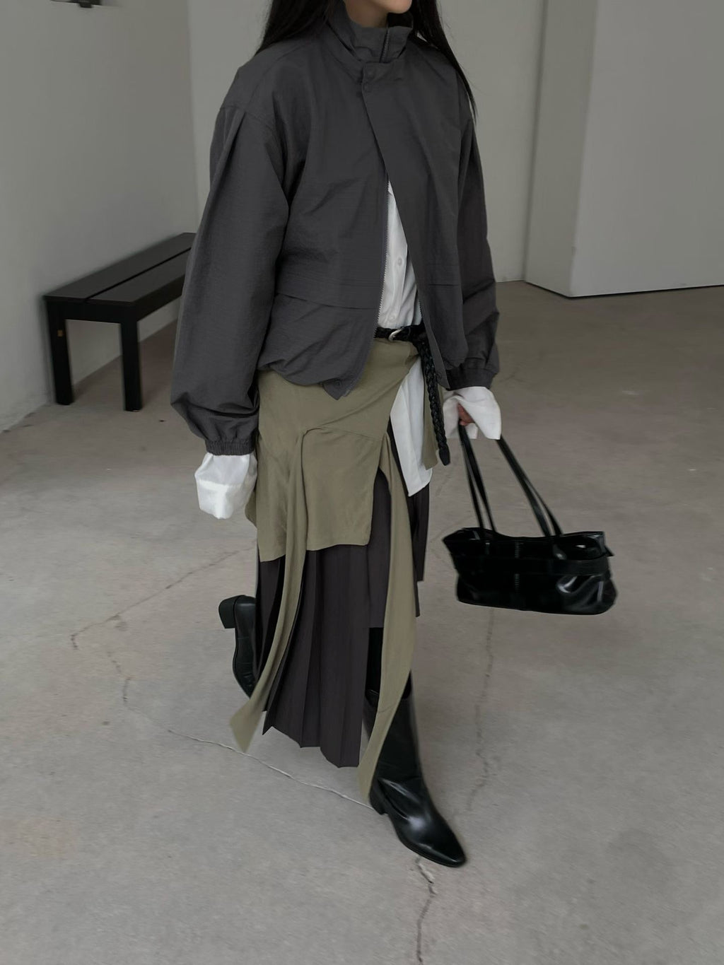 Charcoal high-neck jacket styled with a layered skirt and black boots, walking view