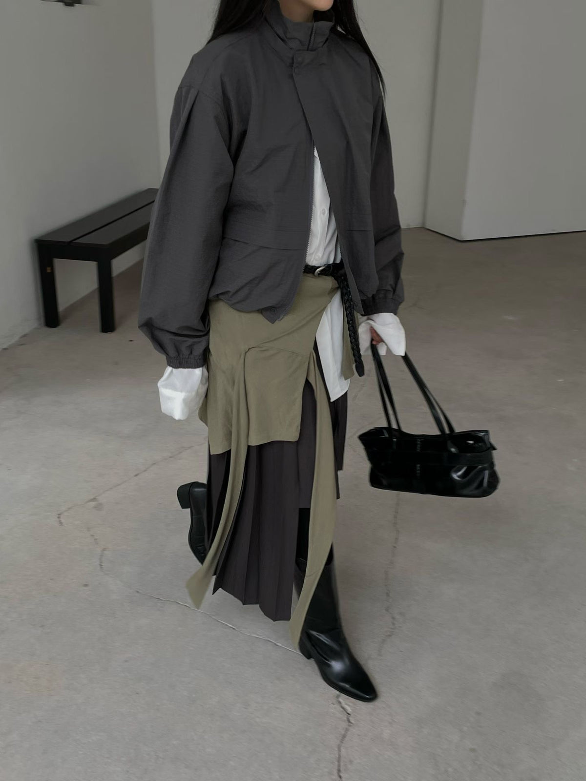 Charcoal high-neck jacket styled with a layered skirt and black boots, walking view