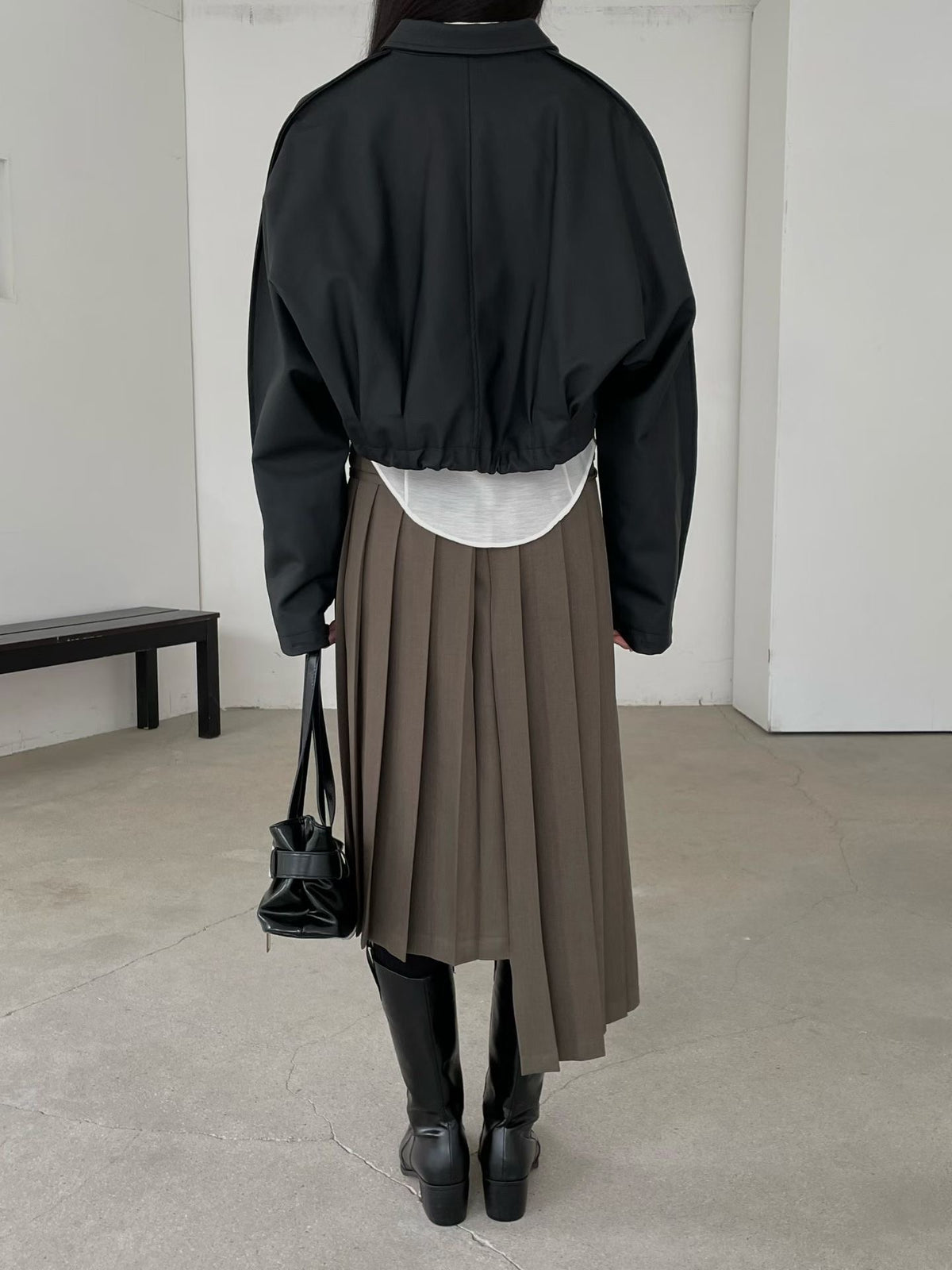 Back view of black cropped faux leather jacket with gathered hem and centre seam