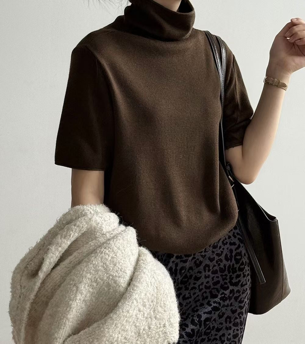 Woman wearing a black short sleeve mock neck sweater with a leopard-print skirt.