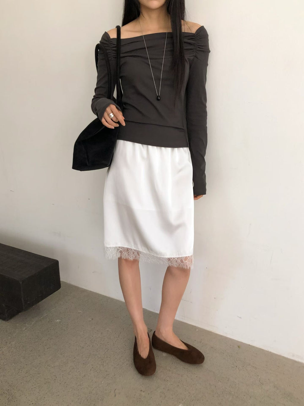 Close-up of a charcoal off-shoulder long sleeve top with gathered shoulder details.