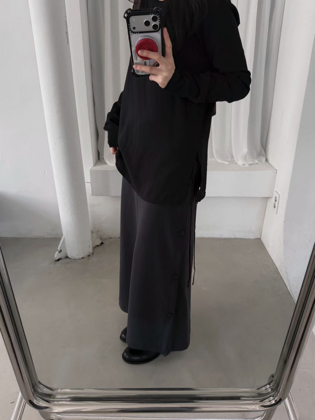 Angled view of a charcoal maxi skirt with gathered side styling worn with a brown sweater.