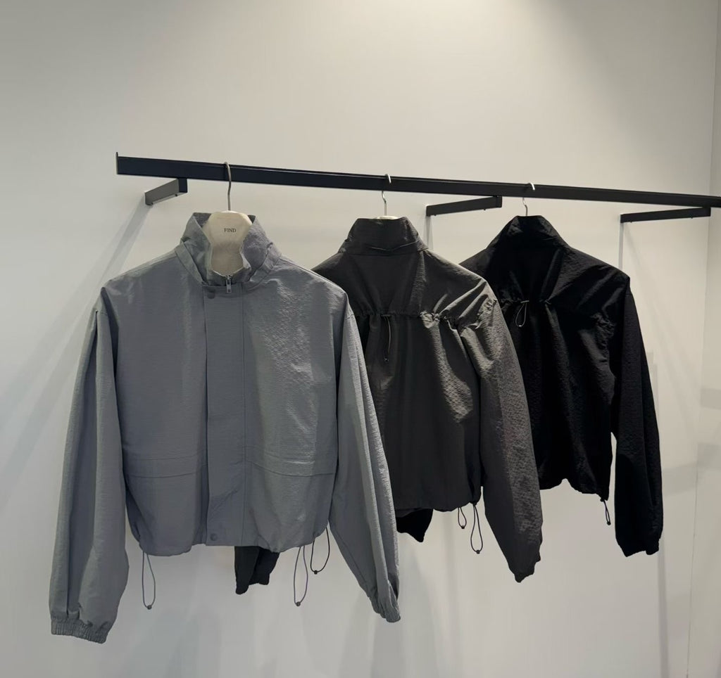Blue Grey, Charcoal and Black high-neck jackets on hangers with hem drawstrings