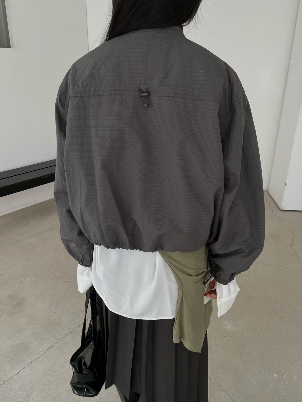 Back view of charcoal jacket showing back yoke, loop detail and gathered hem