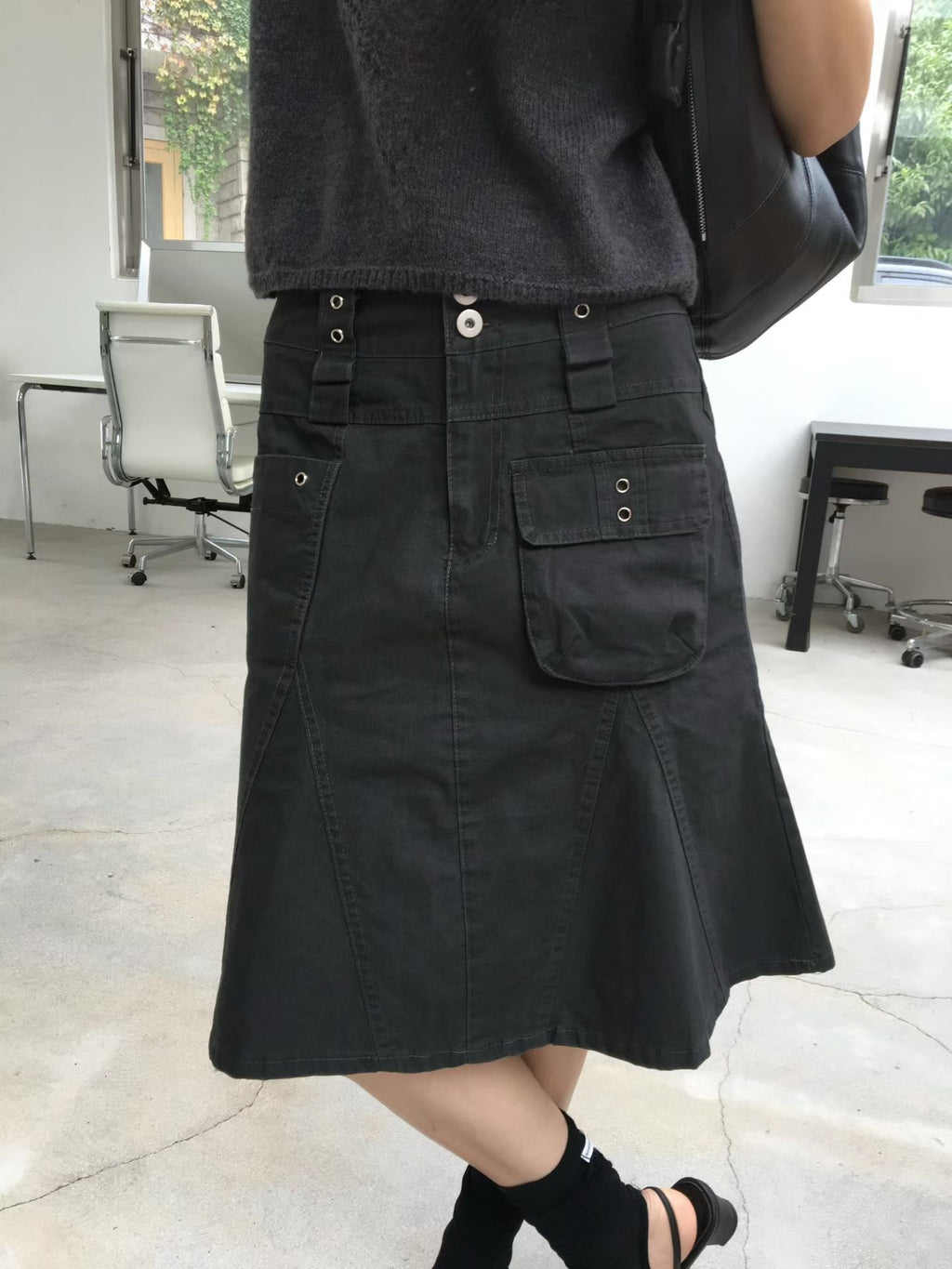 Front outfit view of a charcoal cargo skirt styled with a grey short sleeve top and black sandals.