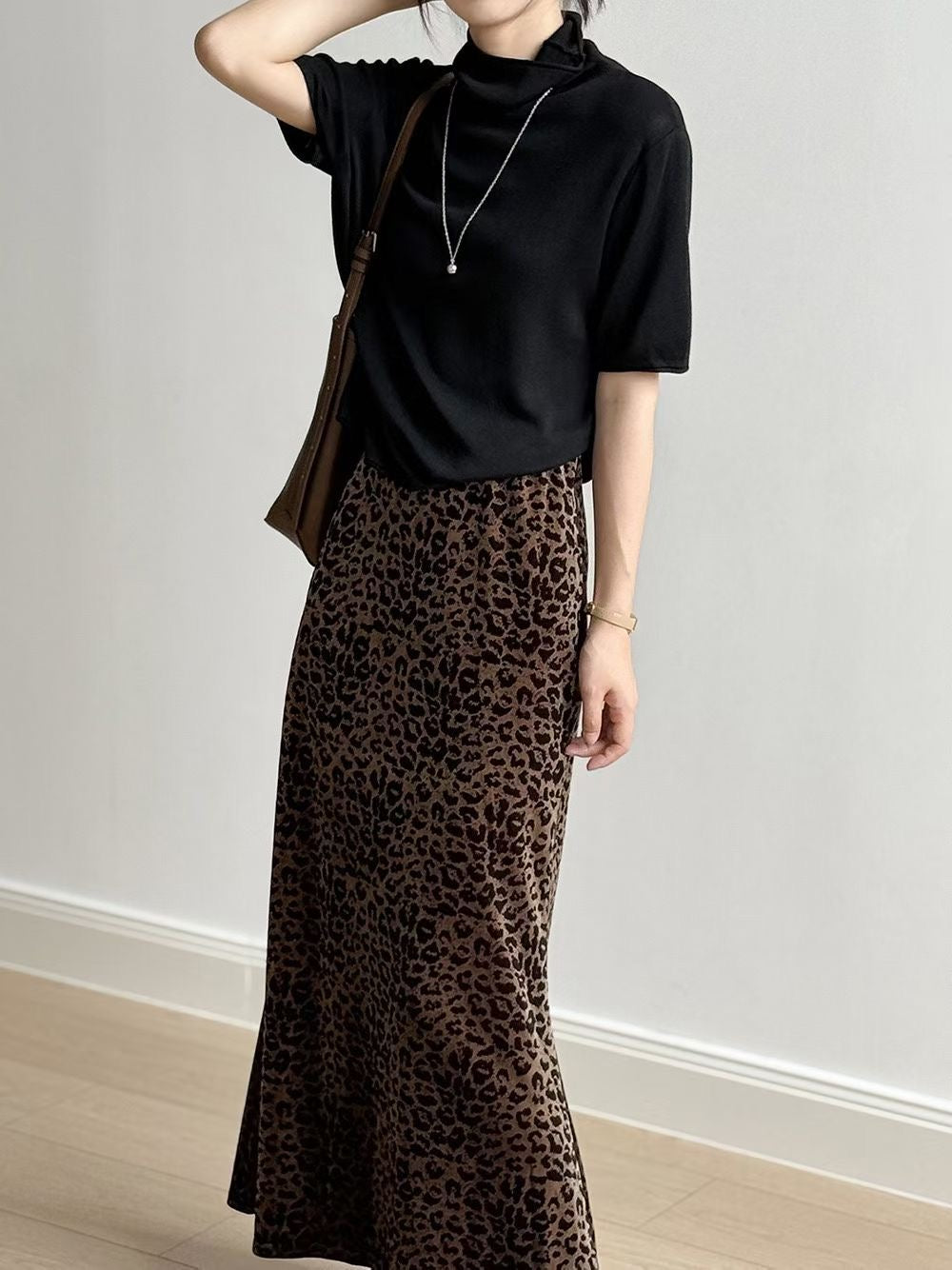 Close-up of a brown short sleeve mock neck sweater styled with a leopard-print skirt.