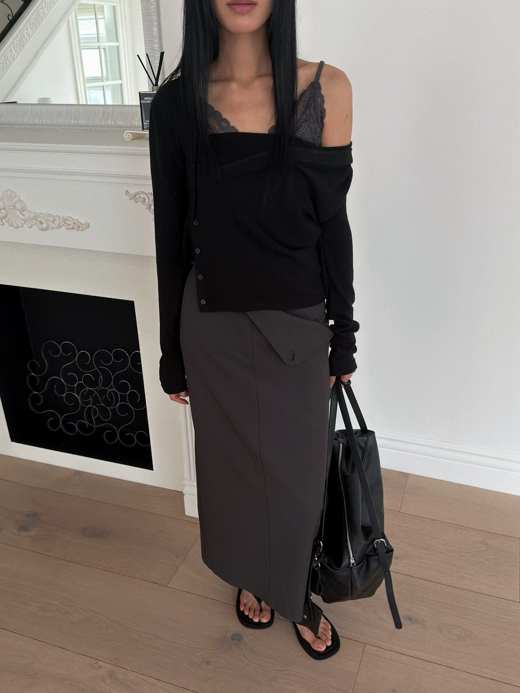 Front view of an ivory draped button cardigan styled with black trousers.