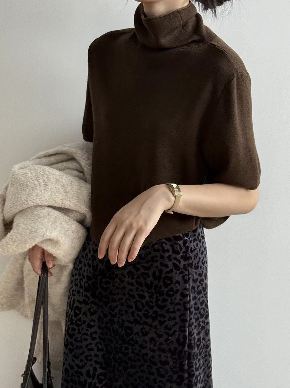 Ivory short sleeve mock neck sweater worn with the sleeve edge turned up.