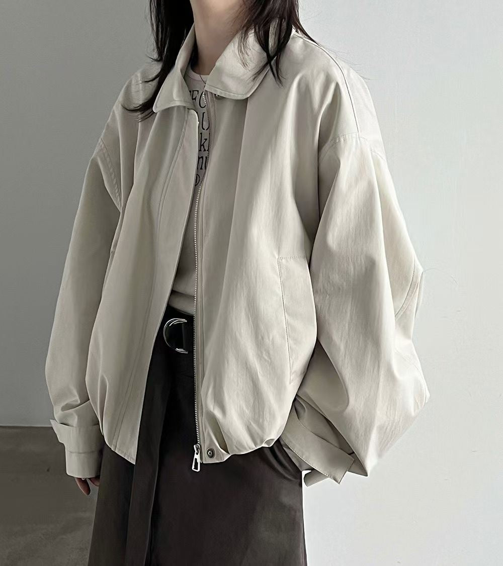 Black and ivory collared blouson jackets laid out showing their front panels and long sleeves.