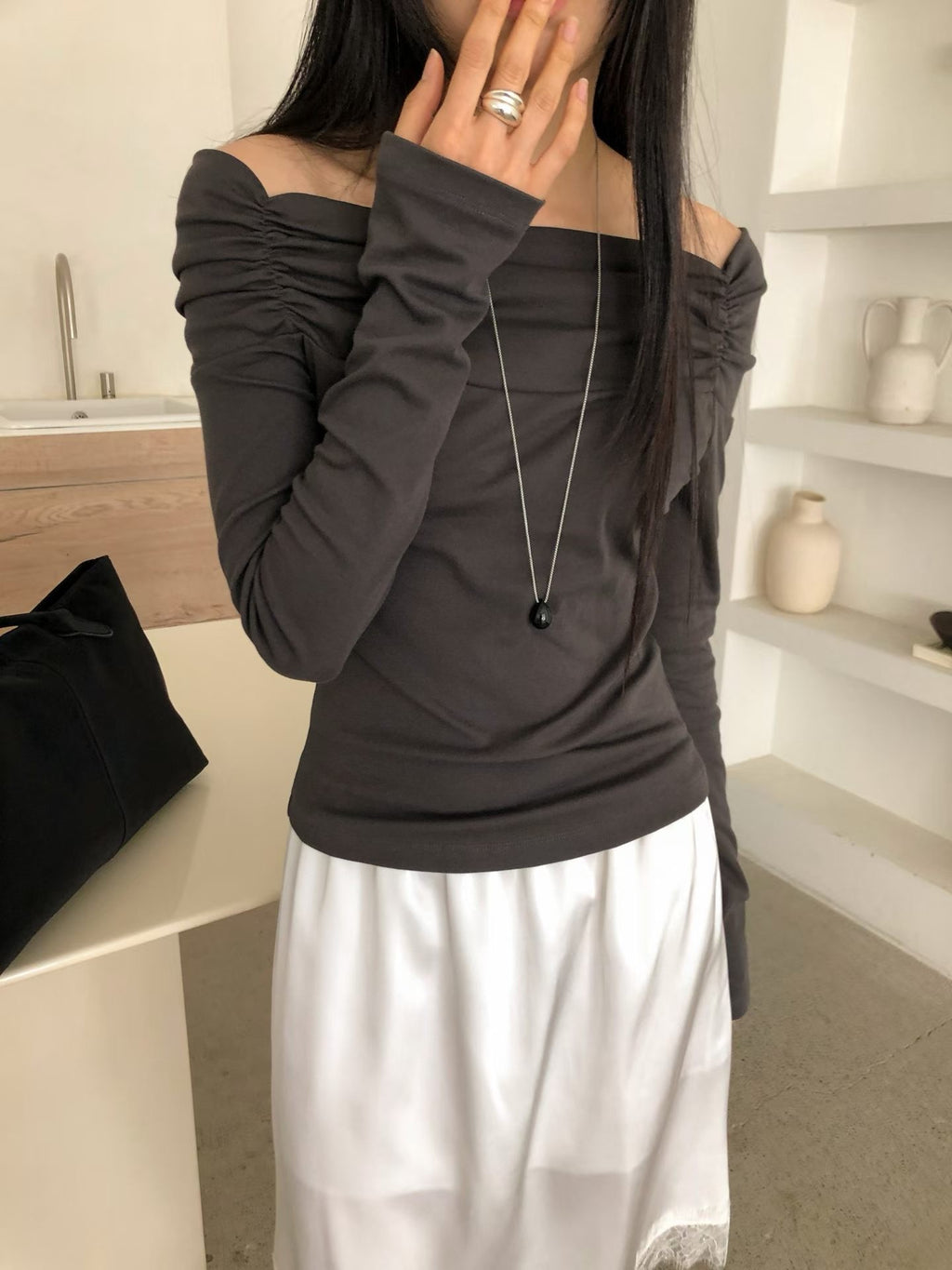 Front view of a charcoal off-shoulder top showing long sleeves and shoulder ruching.