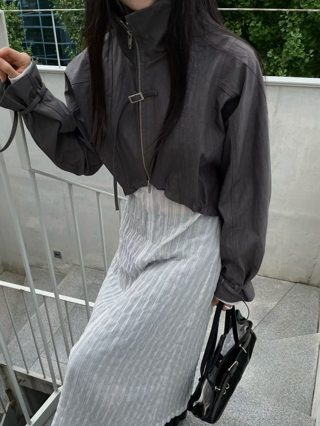 Charcoal cropped bolero jacket with stand collar and buckle details, worn outdoors