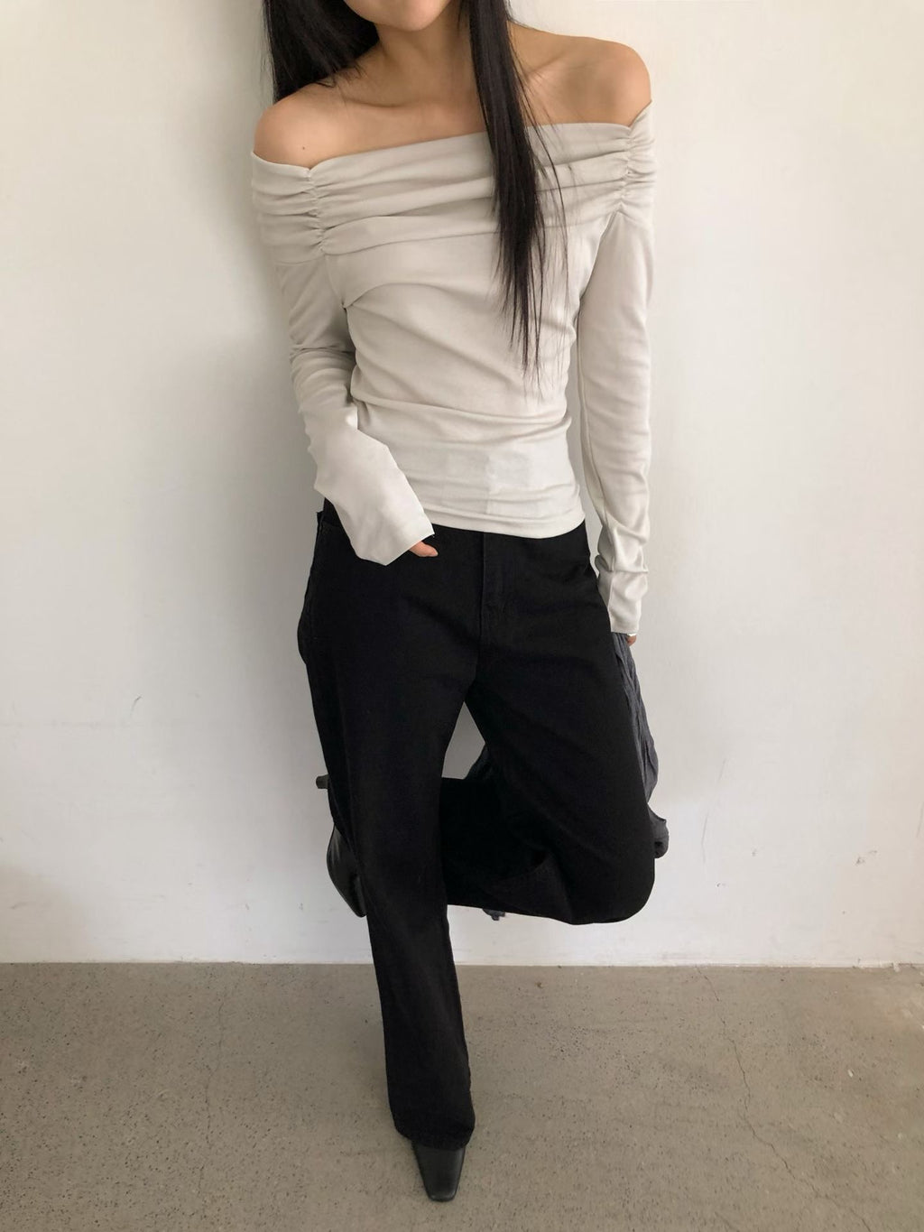 Grey beige off-shoulder long sleeve top styled with black wide leg trousers.