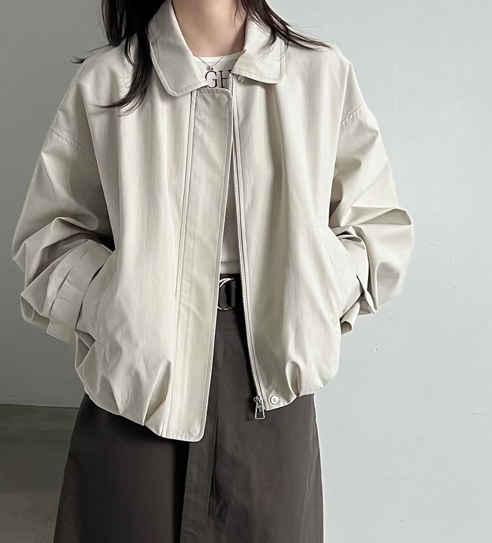 Front view of a black collared blouson jacket worn over a striped top.