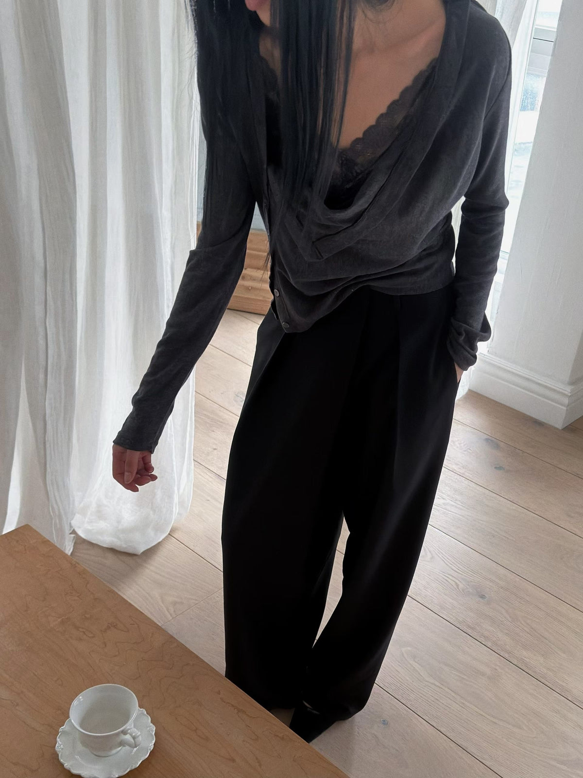 Black asymmetric button cardigan styled off one shoulder with a grey midi skirt.