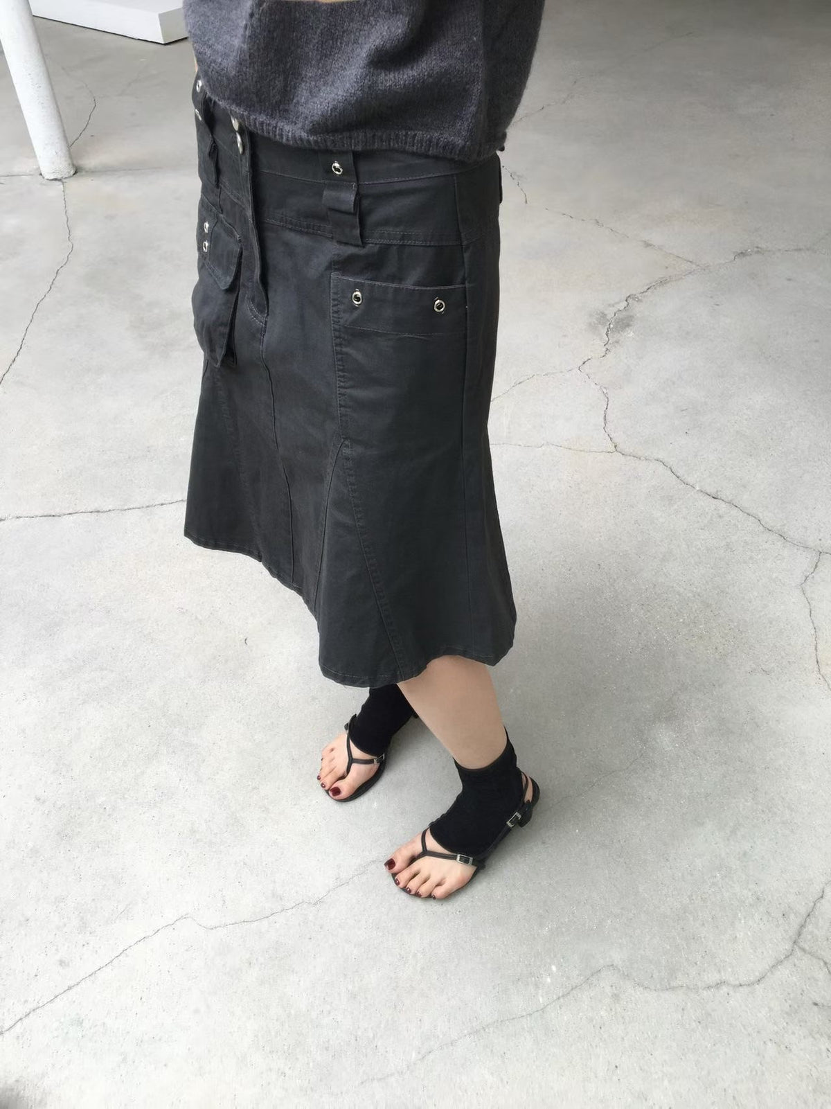 Khaki A-line cargo skirt styled with a black long sleeve top, white belt and black boots.