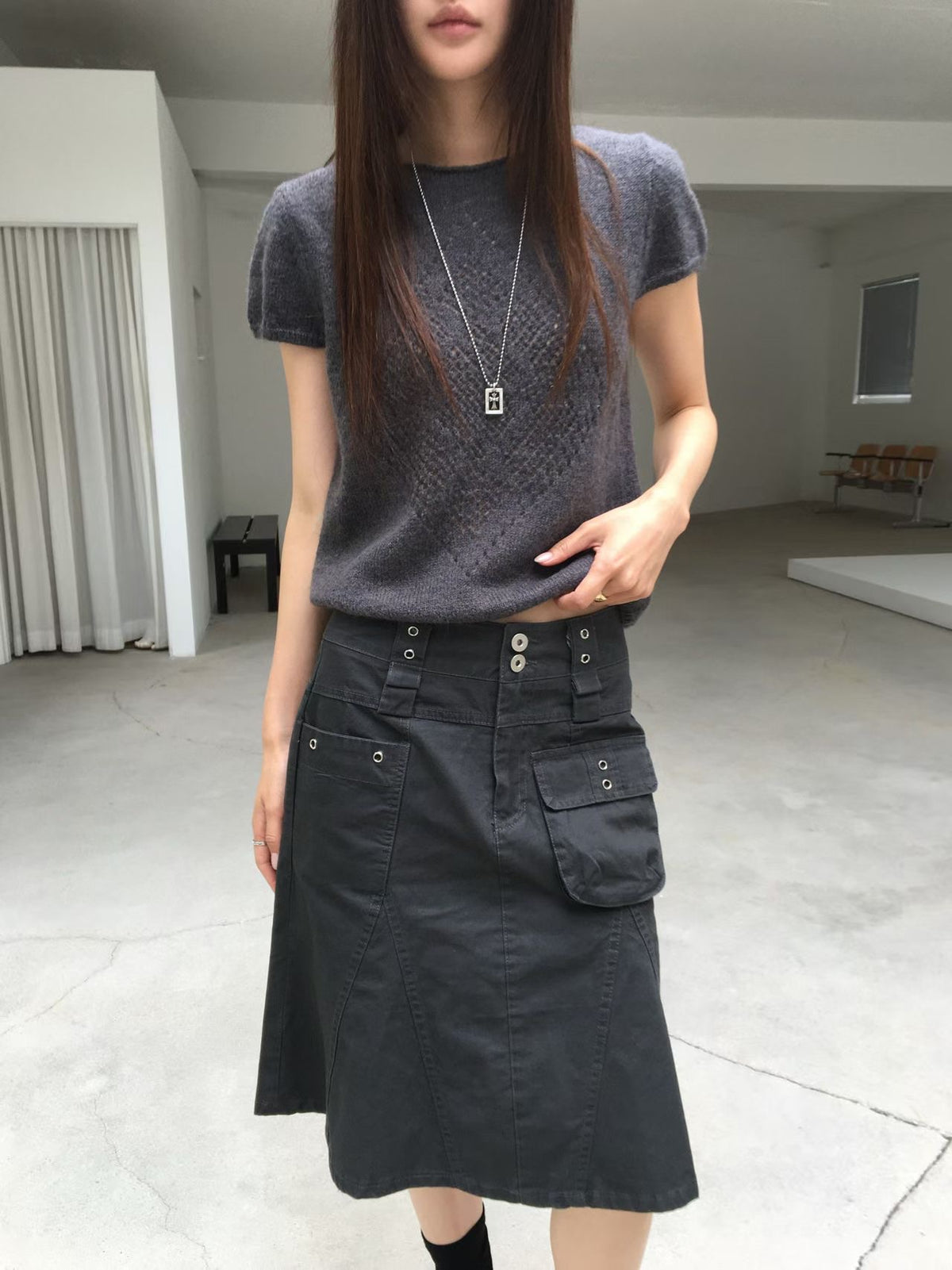 Full-length front view of a charcoal cargo skirt with a grey top and black sandals.