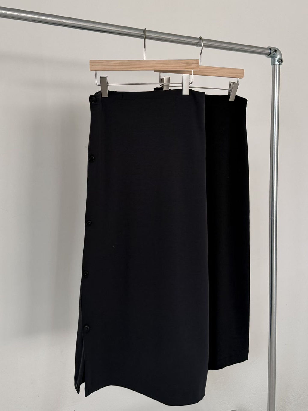 Side view of a charcoal maxi skirt with draped folds worn with a brown sweater.