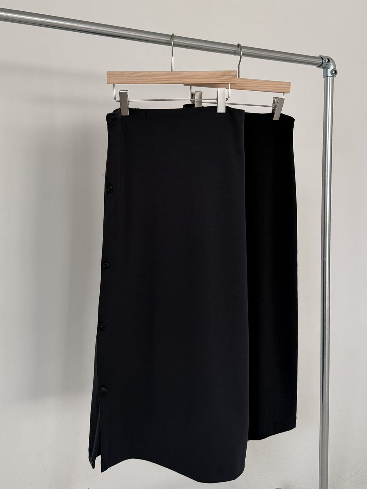 Side view of a charcoal maxi skirt with draped folds worn with a brown sweater.