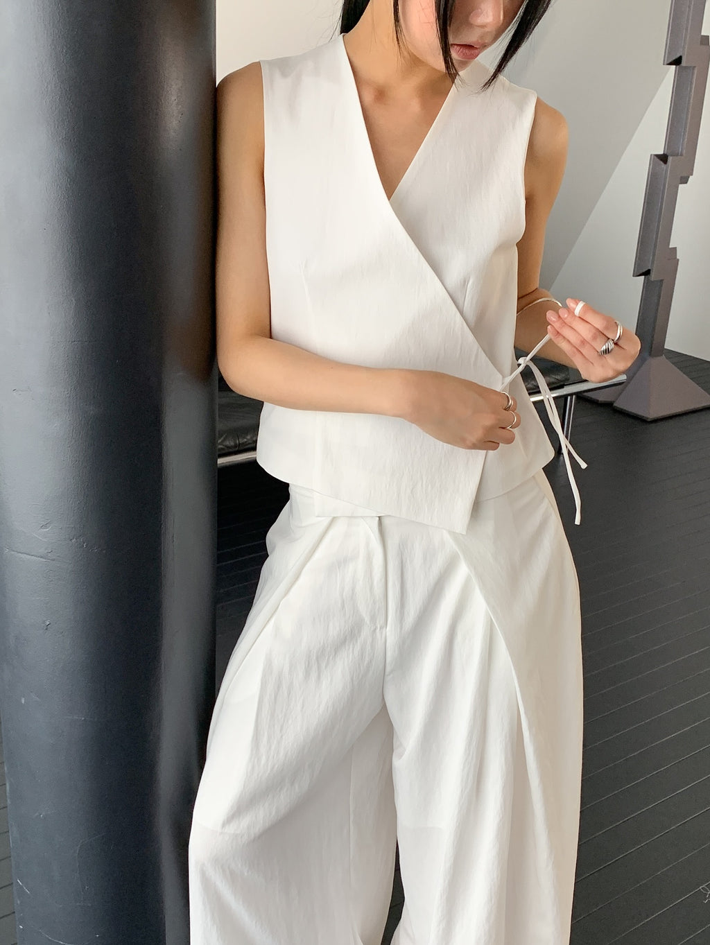 Vivel cross wrap vest in White, styled on model front view with white wide leg pants leaning on black pillar