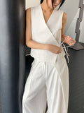 Vivel cross wrap vest in White, styled on model front view with white wide leg pants leaning on black pillar