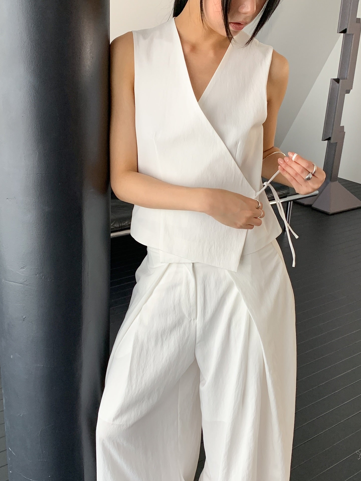 Vivel cross wrap vest in White, styled on model front view with white wide leg pants leaning on black pillar