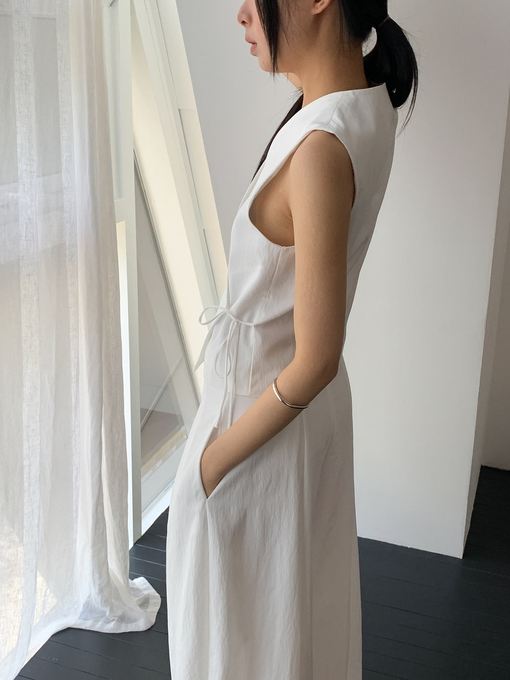 Vivel cross wrap vest in White, styled on model front view close-up tie string detail with white wide leg pants