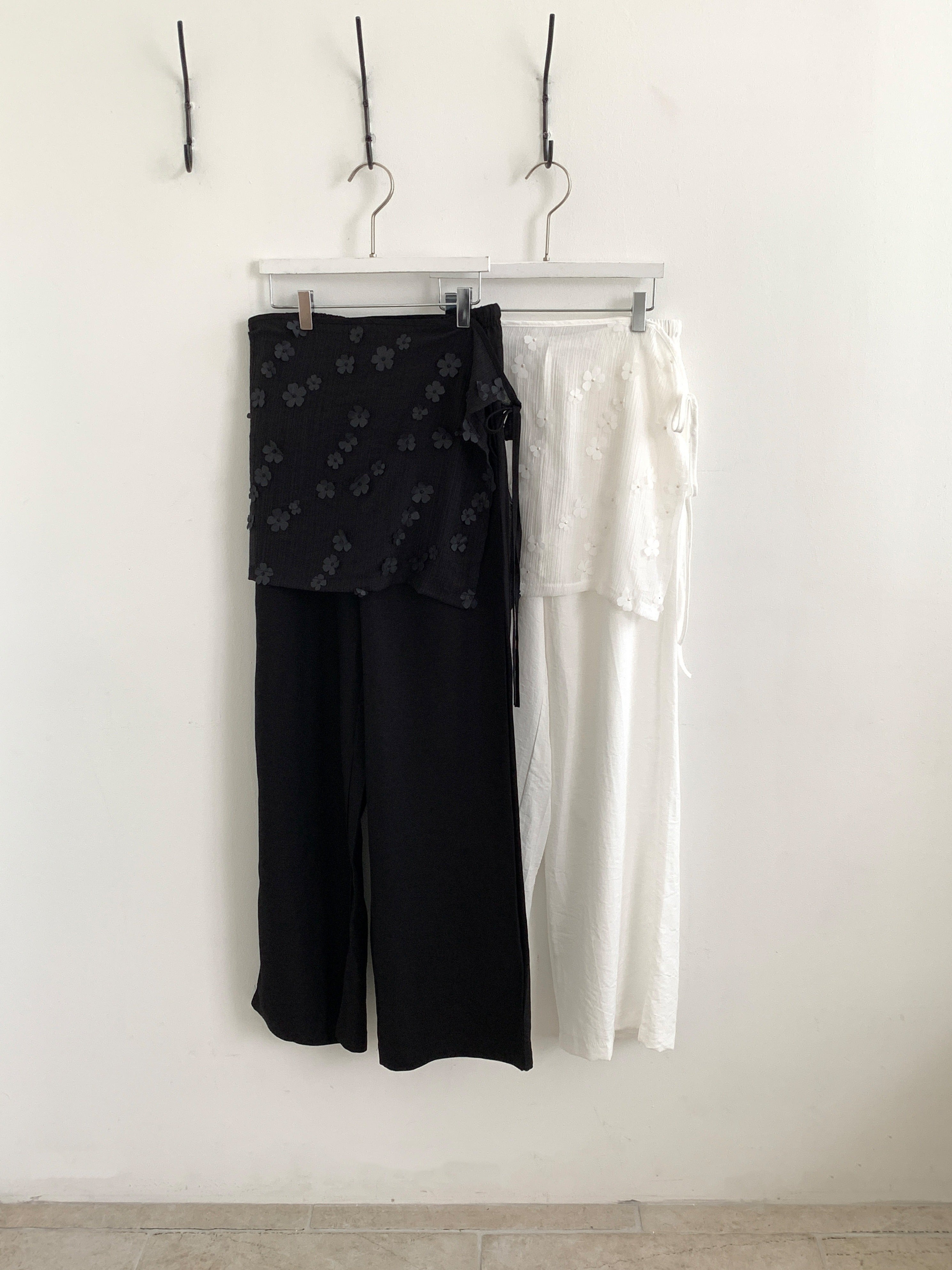 Merrymore floral overlay wrap layered wide leg pants in White, product flat lay on wooden table with black knit top and flip flops