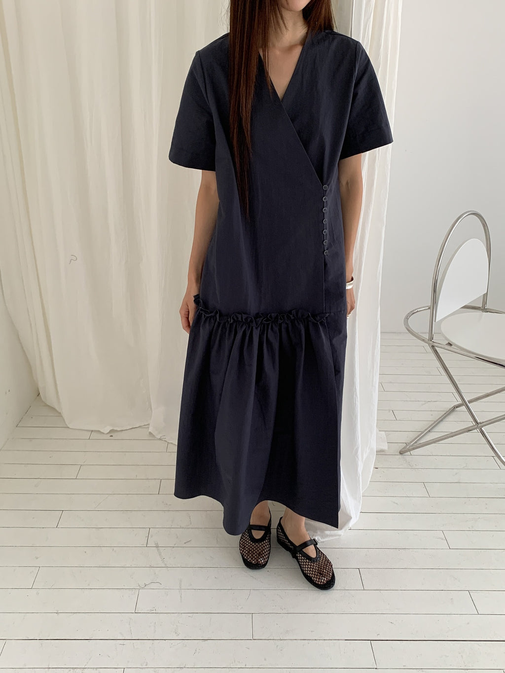 Vivel wrap shirring maxi dress in Charcoal, styled on model front view full length standing by black console table