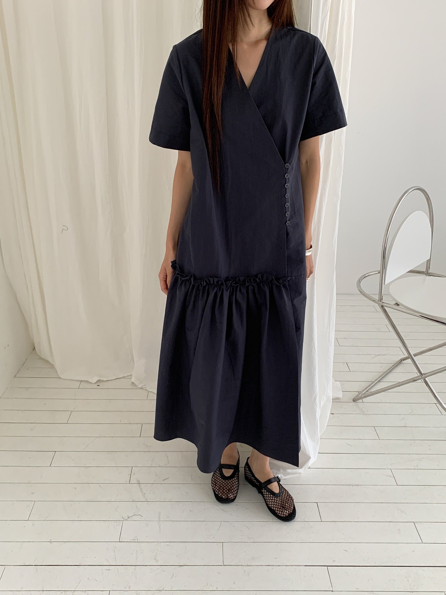 Vivel wrap shirring maxi dress in Charcoal, styled on model front view full length standing by black console table