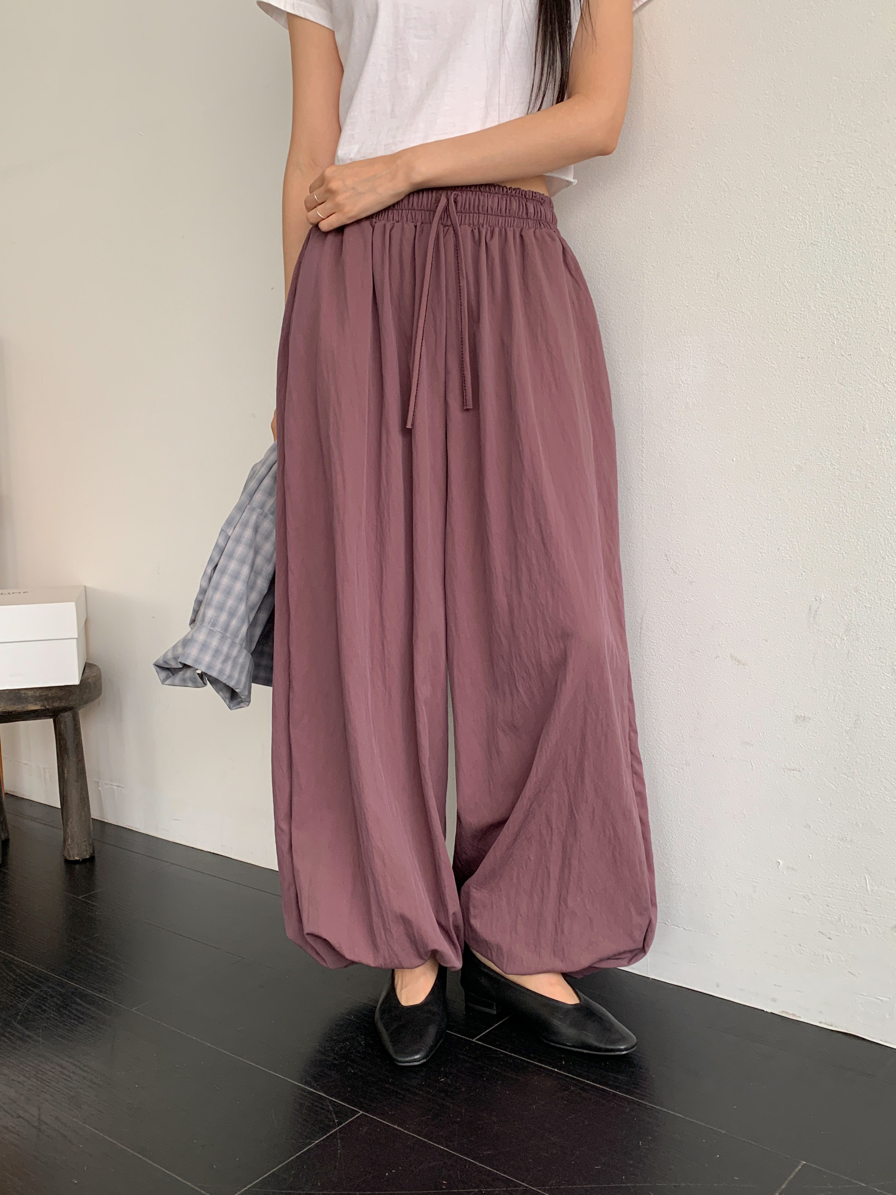 Merrymore drawstring elastic waist harem pants in Burgundy, styled on model front view close-up drawstring waist detail with grey check shirt tied at waist