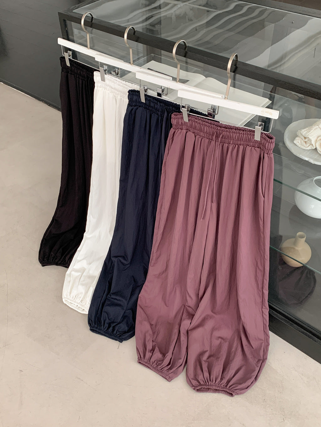 Merrymore drawstring elastic waist harem pants in Black, Navy, Ivory and Burgundy, four colorways on hanger rack front view