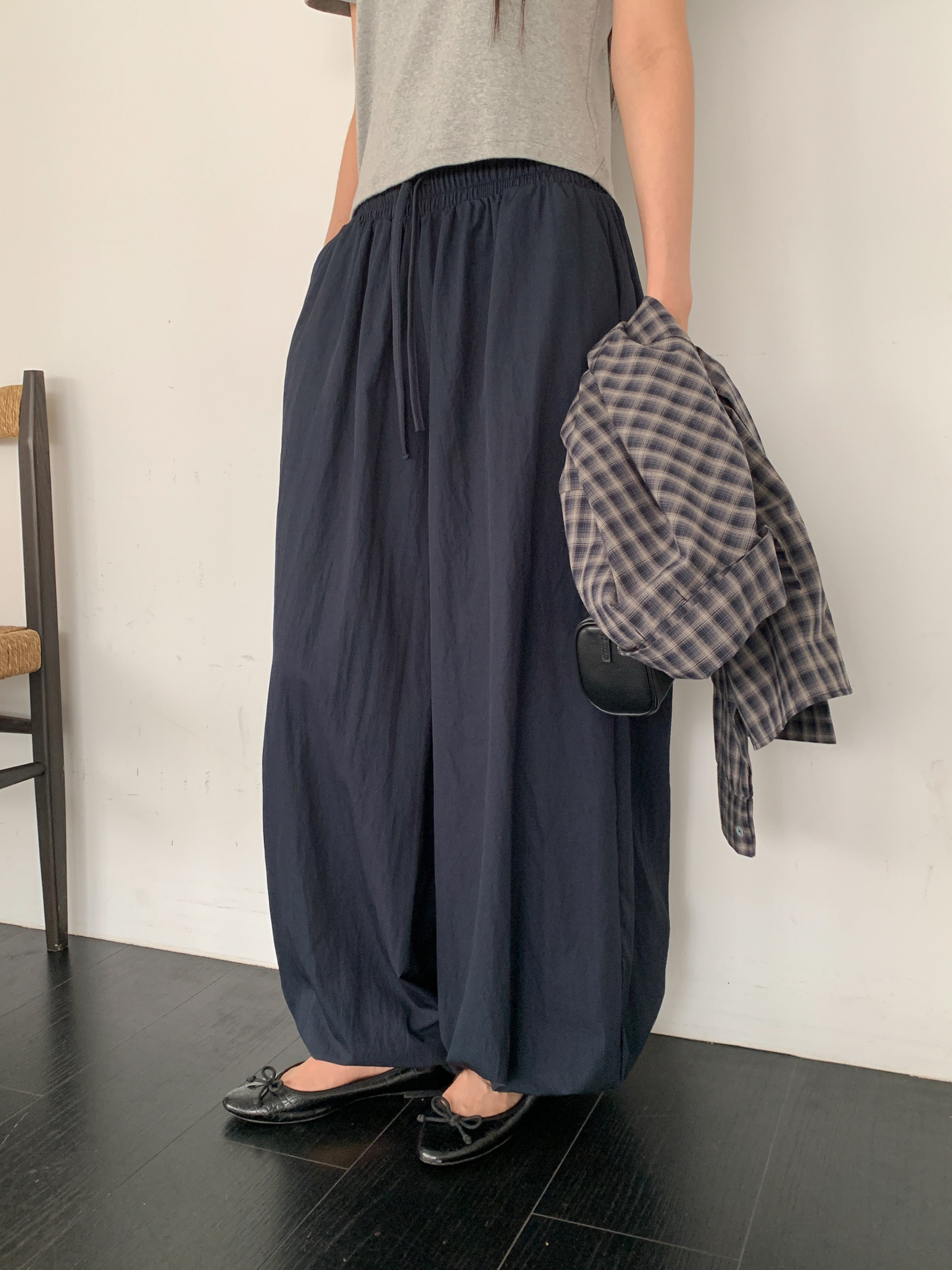 Merrymore drawstring elastic waist harem pants in Navy, styled on model front view with grey tank top and check shirt in hand full length