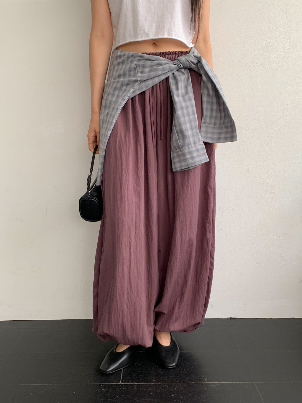 Merrymore drawstring elastic waist harem pants in Burgundy, styled on model front view with white crop top and grey check shirt tied at waist full length