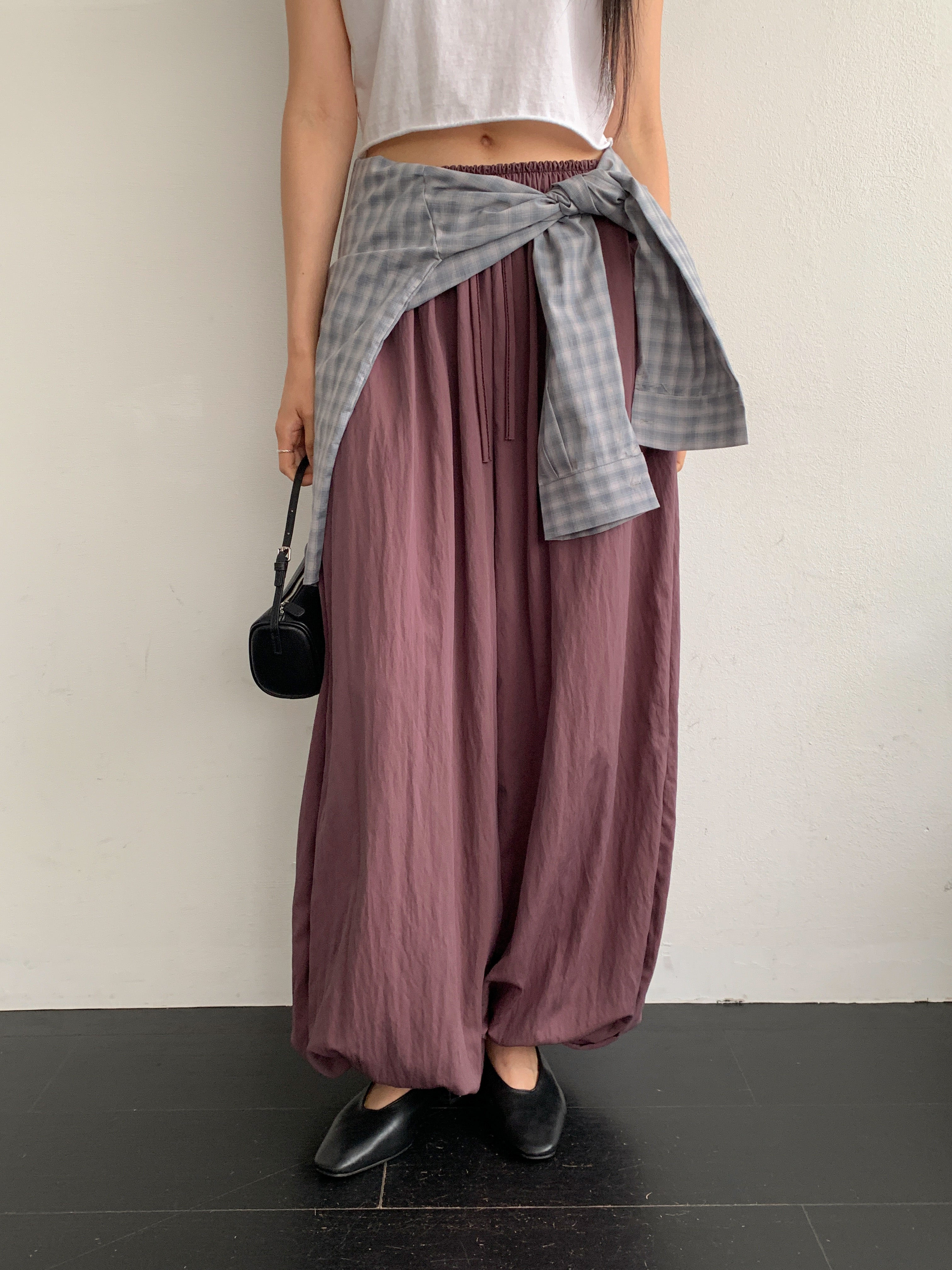 Merrymore drawstring elastic waist harem pants in Burgundy, styled on model front view with white crop top and grey check shirt tied at waist full length