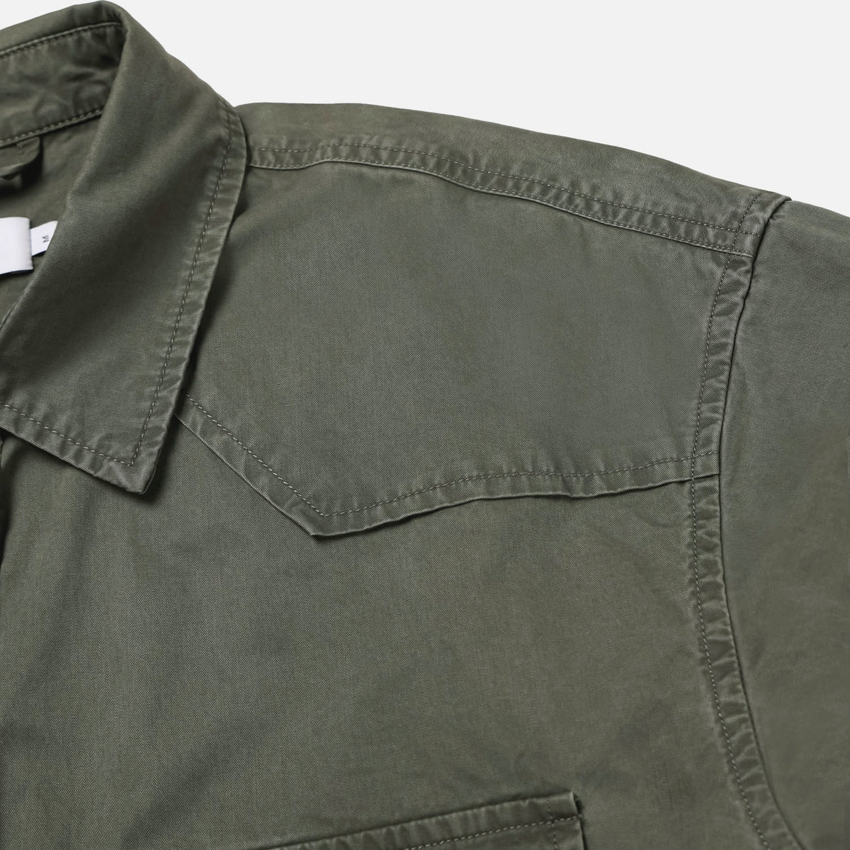 Curved hem and washed seam detail on a khaki cotton western shirt