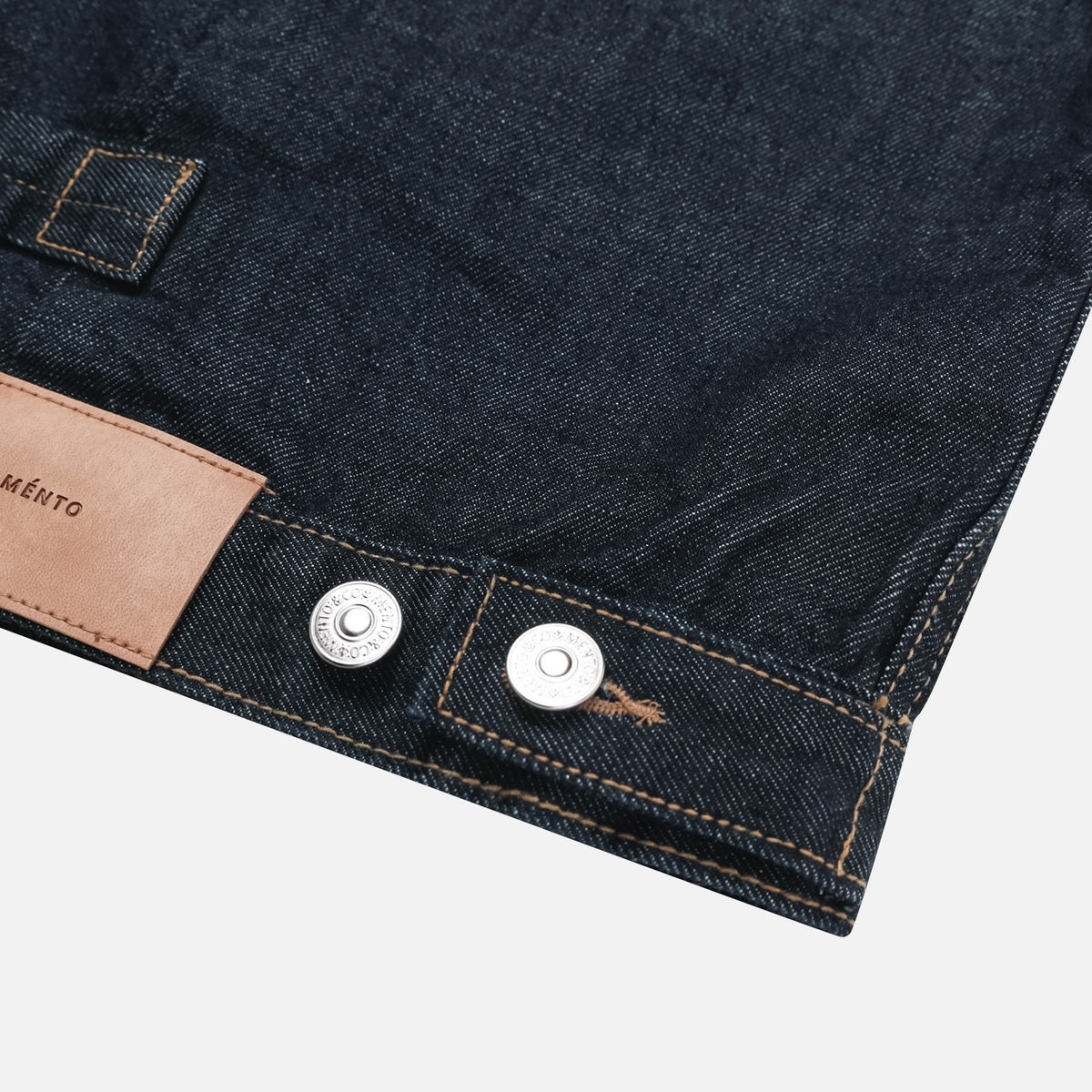 Metal buttons and waist adjustment detail on a raw indigo denim jacket
