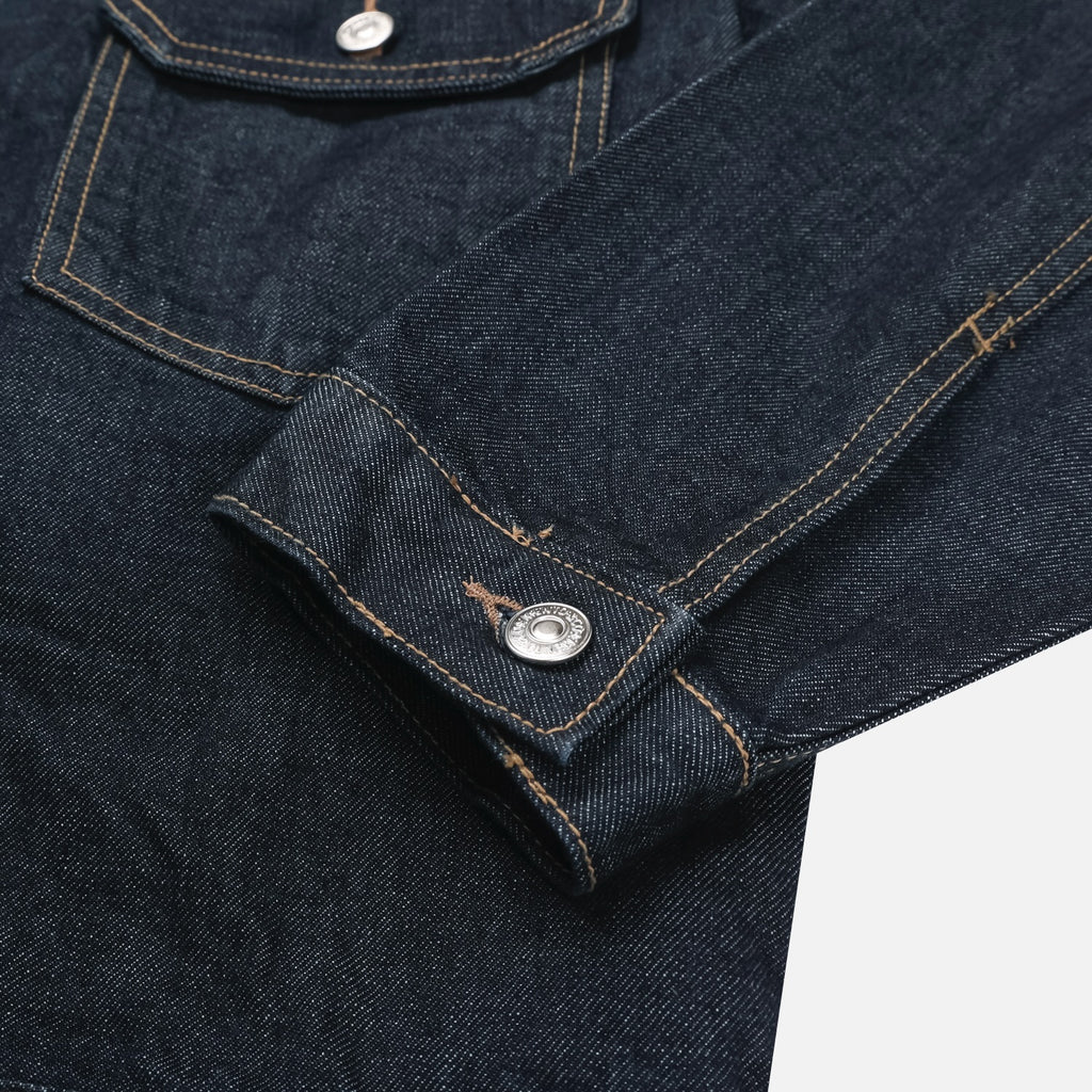 Adjustable back waist tab and Mento label on a raw indigo denim jacket