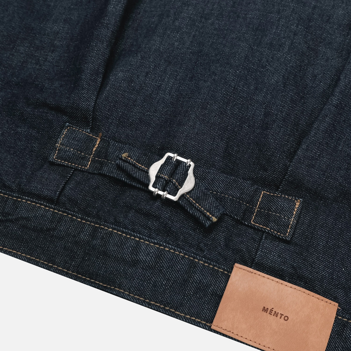 Metal button placket and contrast stitching on a dark indigo denim jacket