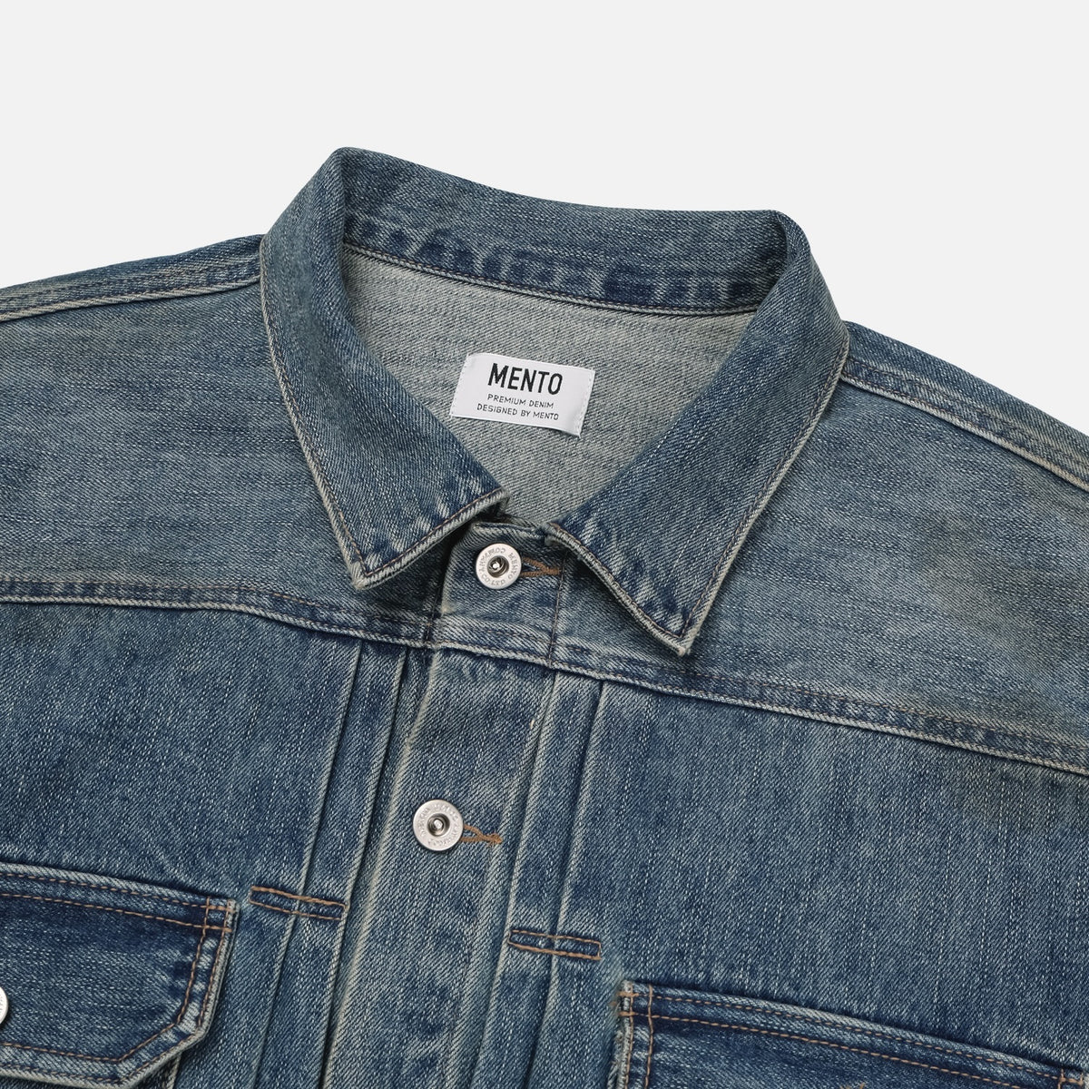 Adjustable back waist tab and Mento label on a mid-wash denim jacket
