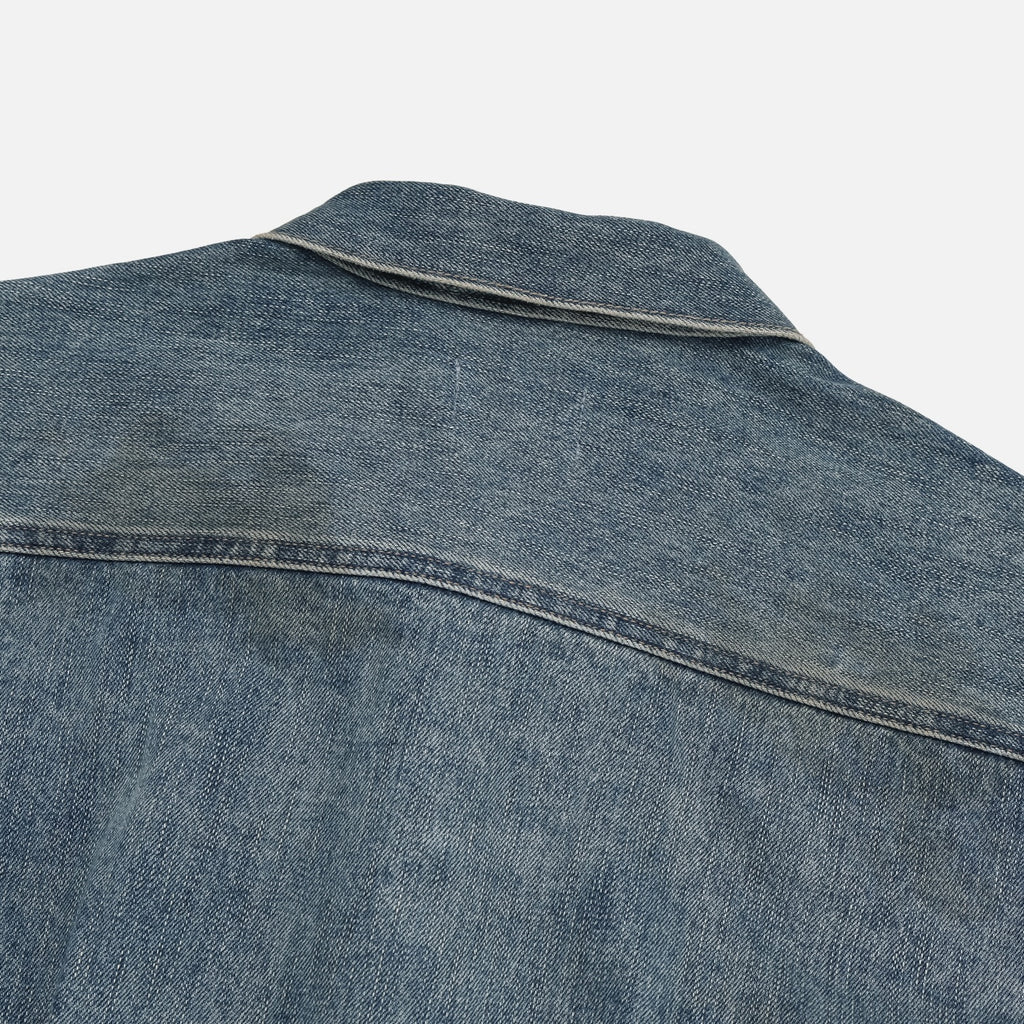 Flap chest pocket and metal button detail on a mid-wash denim jacket