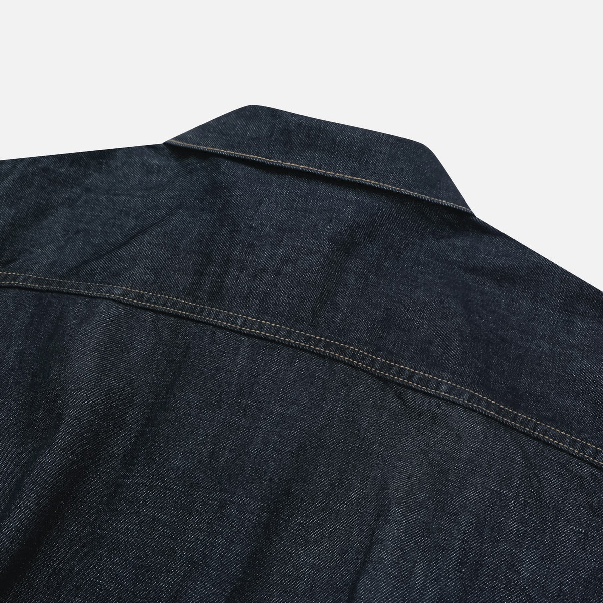 Flap chest pocket and contrast stitching on a raw indigo denim jacket