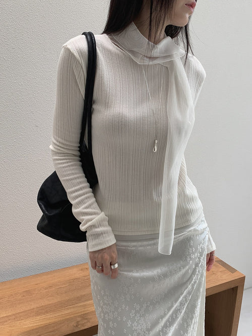 Front view of a cream ribbed long sleeve top with neckline ties hanging loose.