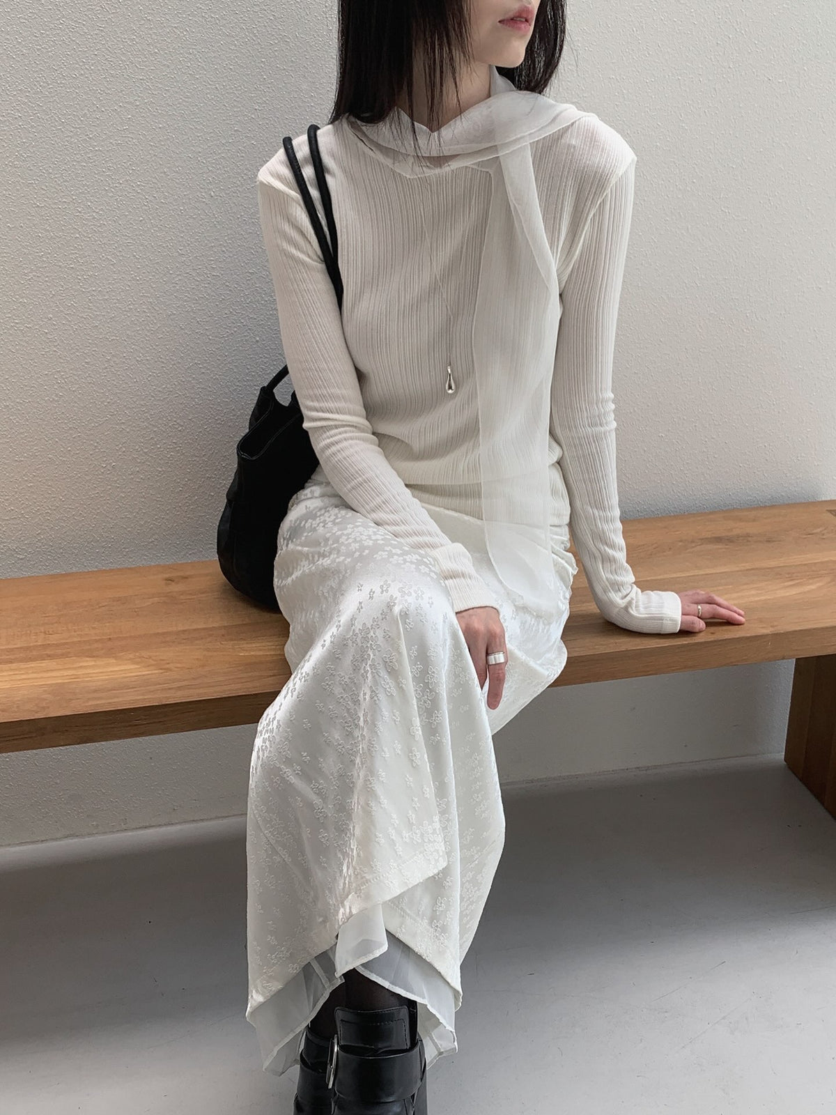 Close-up of a cream ribbed top showing long sleeves and a knotted neckline tie.