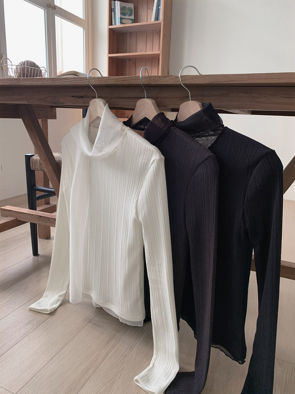 Cream, brown and black ribbed long sleeve tops with neckline ties on wooden hangers.