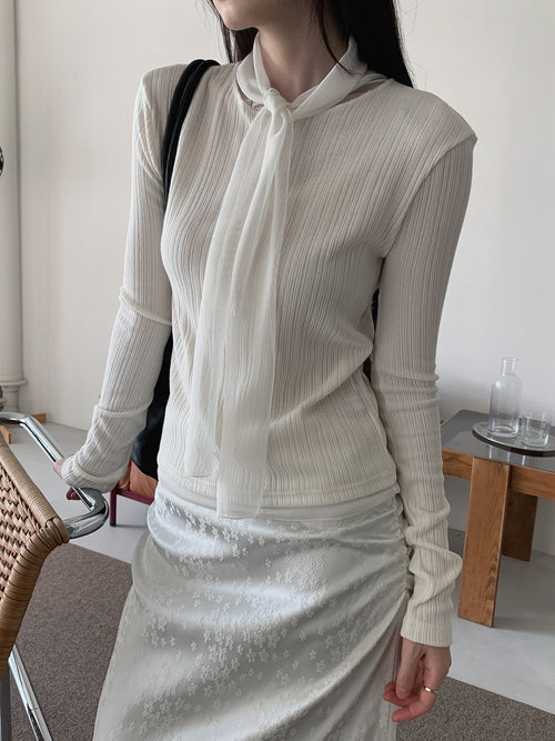 Cream ribbed long sleeve top with a neck tie draped down the front, styled with a floral skirt.