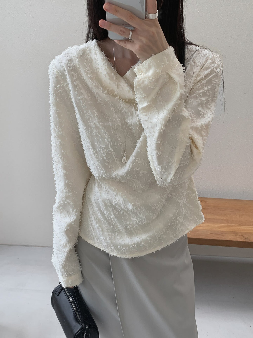 Back view of a cream textured blouse showing waist ties fastened in a bow.