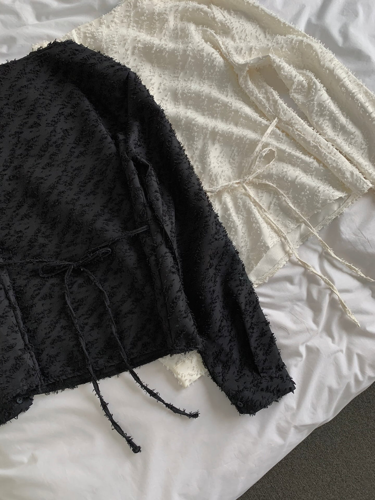 Close-up of the draped neckline and textured fabric of a cream blouse worn by a seated woman.